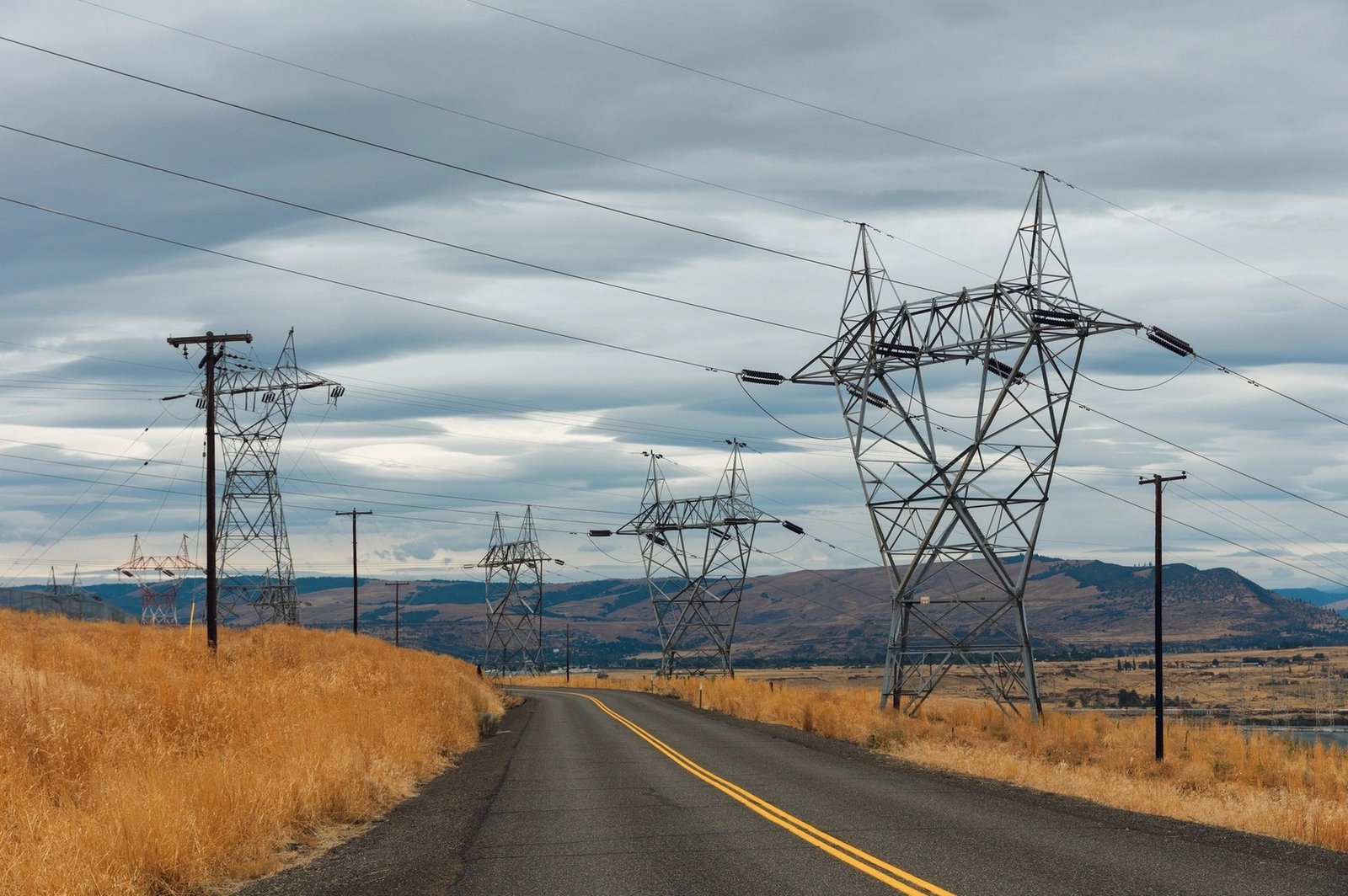 High voltage transmission towers carrying power lines across a rural landscape