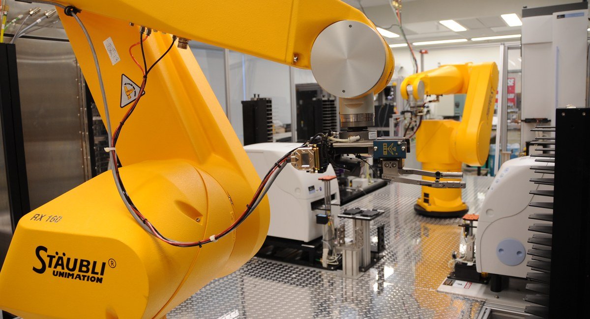 Robotic arms handling assay plates in an automated genomics laboratory