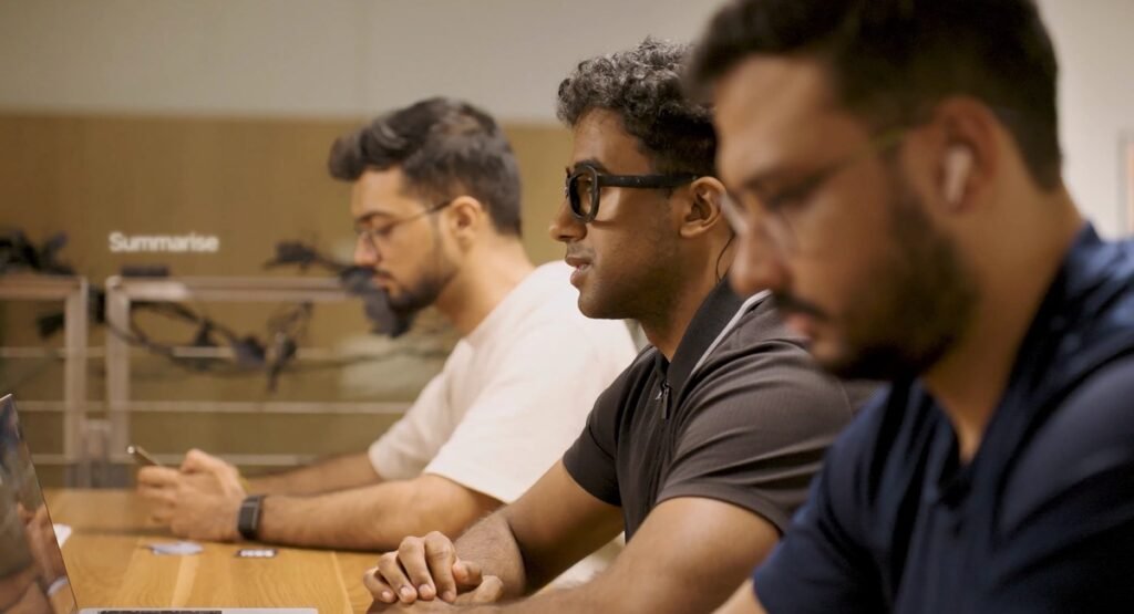 A man wearing Subvocal glasses while working at a shared office table
