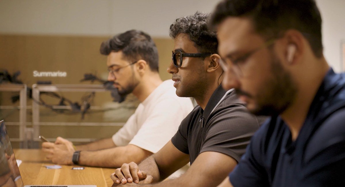 A man wearing Subvocal glasses while working at a shared office table